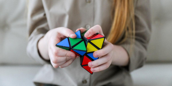 Person spielt mit aus bunten Dreiecken aufgebautem Logikrätsel-Objekt