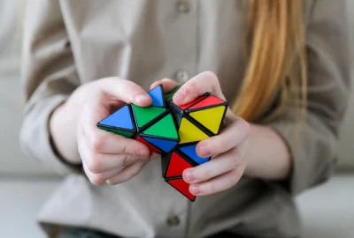 Person spielt mit aus bunten Dreiecken aufgebautem Logikrätsel-Objekt