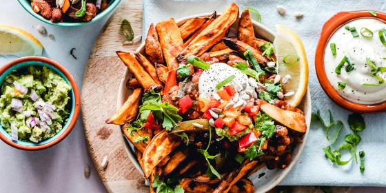 Mehrere Gefäße mit frittierten Kartoffeln und Dips