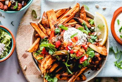 Mehrere Gefäße mit frittierten Kartoffeln und Dips