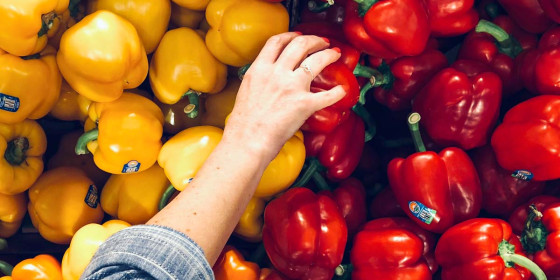 Person greift nach roter Paprika in Auslage