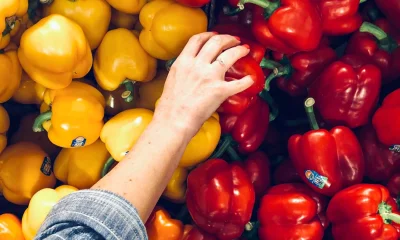 Person greift nach roter Paprika in Auslage