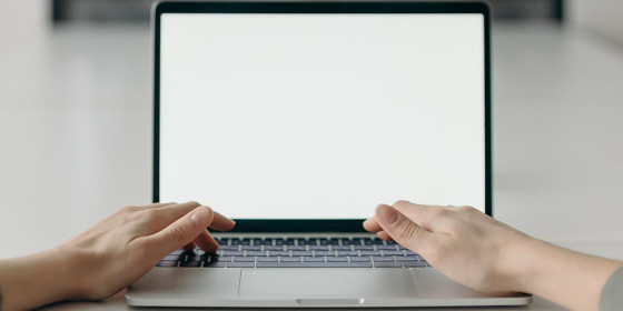 Zwei Hände auf Laptop-Tastatur vor weißem Bildschirm