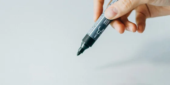 Eine Hand führt einen Filzstift auf ein leeres Blatt Papier