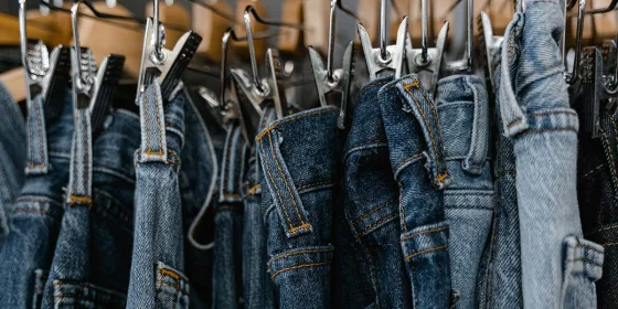 Eine Reihe verschiedenfarbiger Jeans hängt an Bügeln an einer Stange