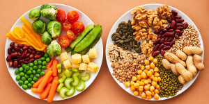 Zwei Teller mit kleingeschnittenem Gemüse, Nüssen, Hülsenfrüchten und Kernen