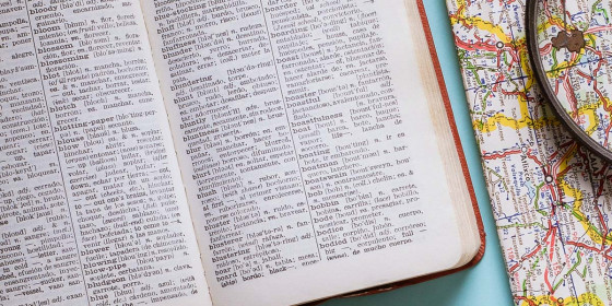 Aufgeschlagenes Wörterbuch neben einer Landkarte